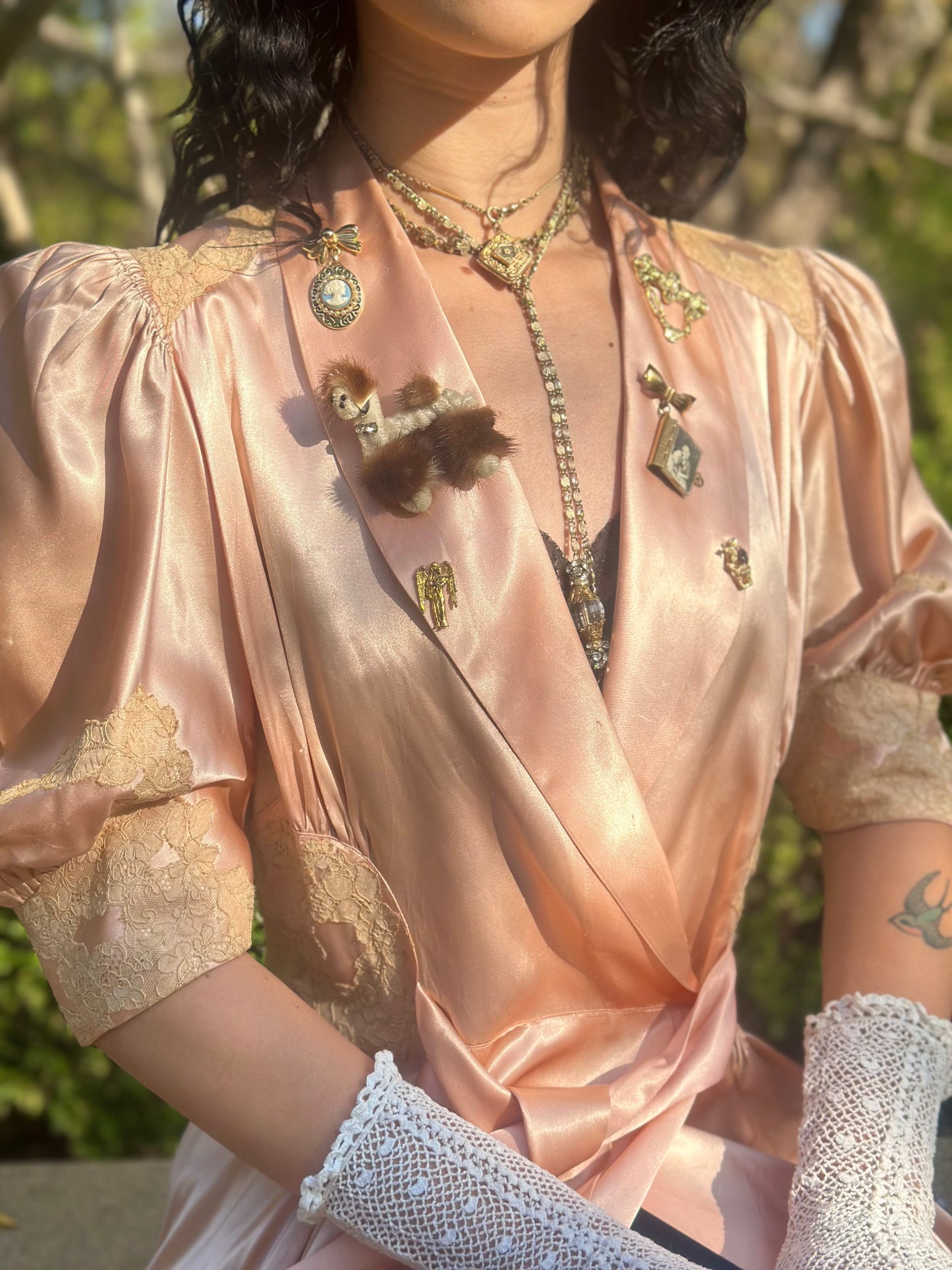 Person wearing a vintage-style dress with lace details and jewelry outdoors.
