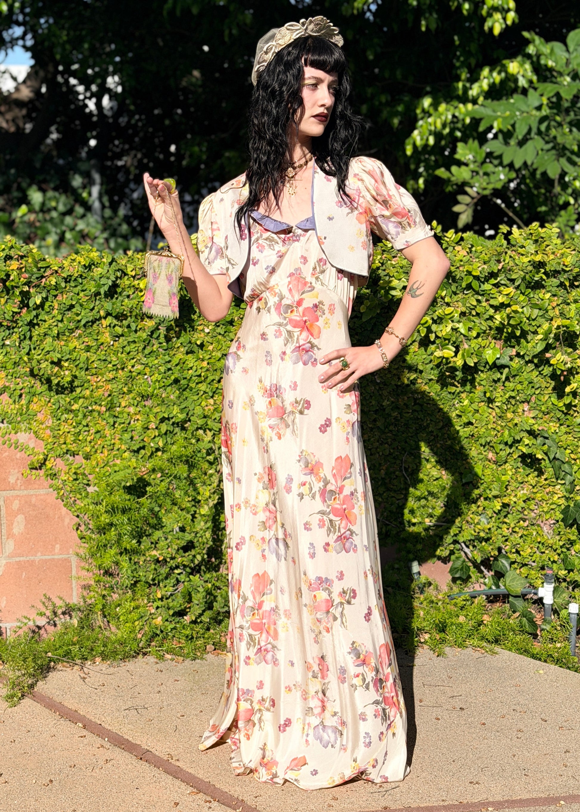 Woman in a floral  antique 1930s floral dress standing outdoors with greenery in the background