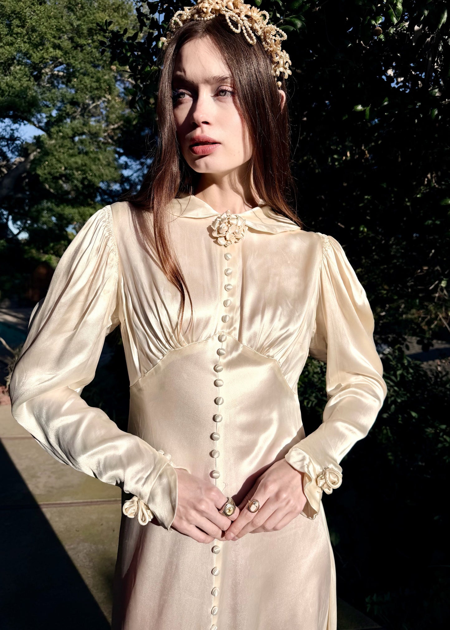 Vintage 1930s wedding gown with long sleeves and decorative buttons on a dark background