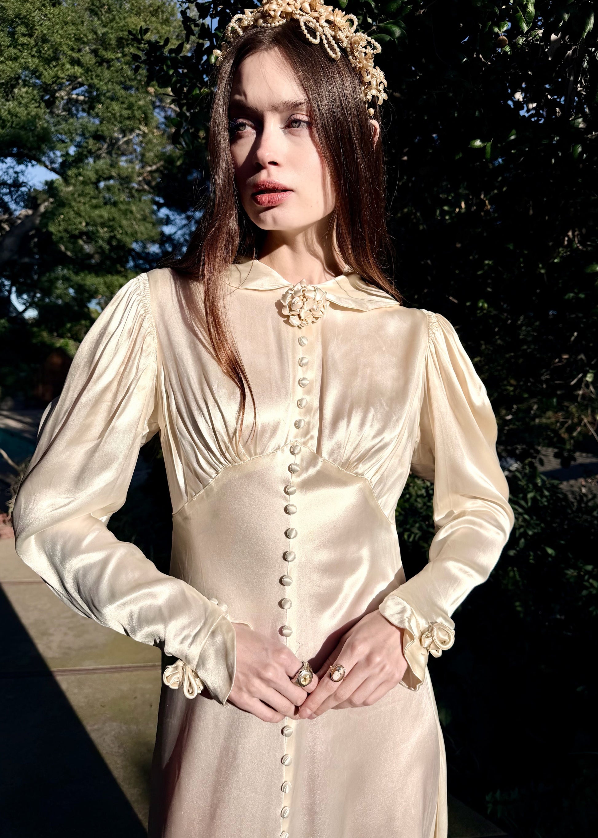 Vintage 1930s wedding gown with long sleeves and decorative buttons on a dark background