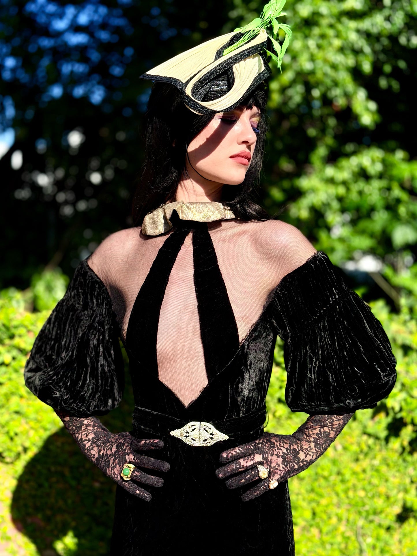 Woman wears antique 1930's black silk velvet Art Deco evening gown in field