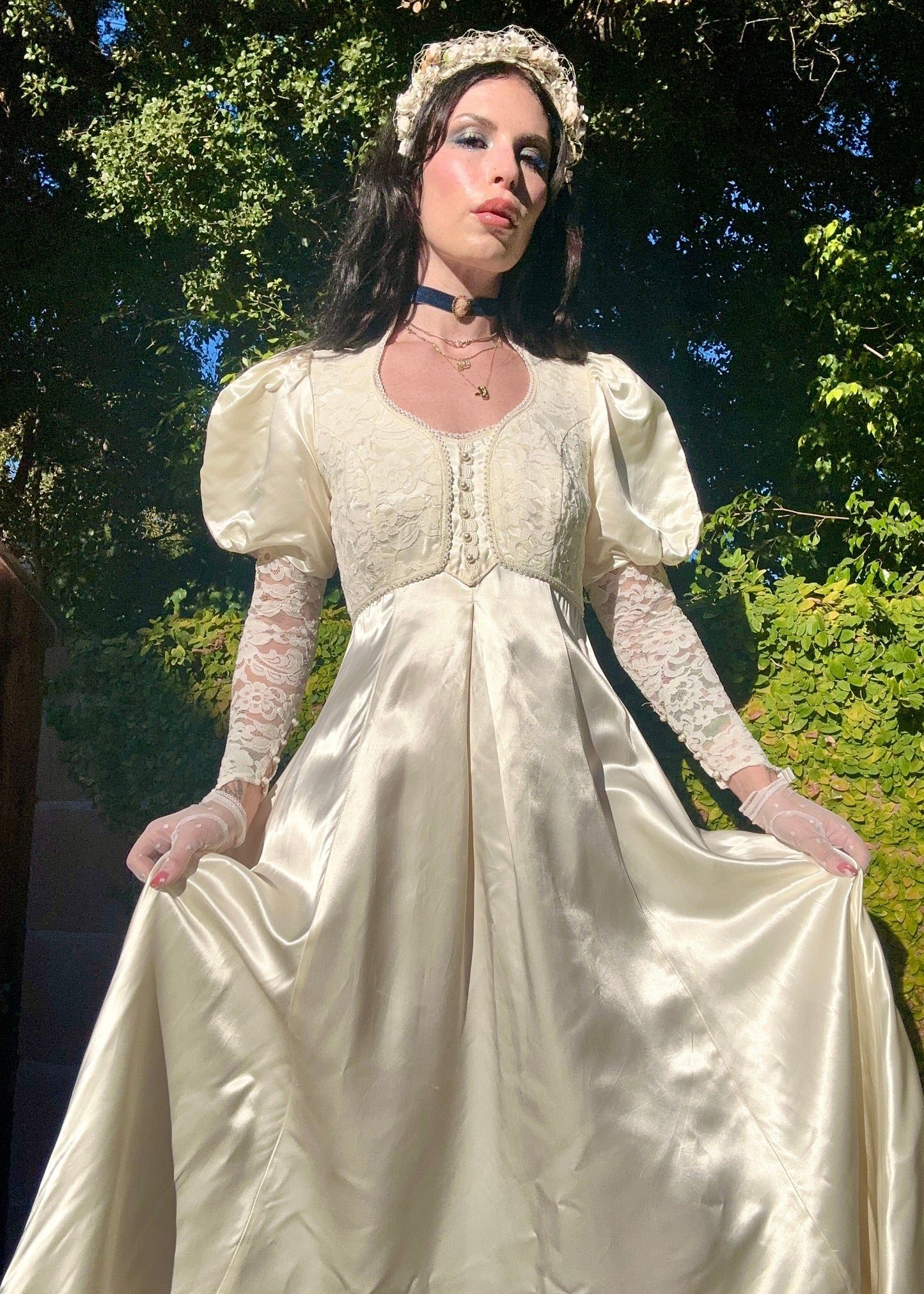 Woman in a Gunne Sax vintage wedding dress with long sleeves and gloves standing outdoors.