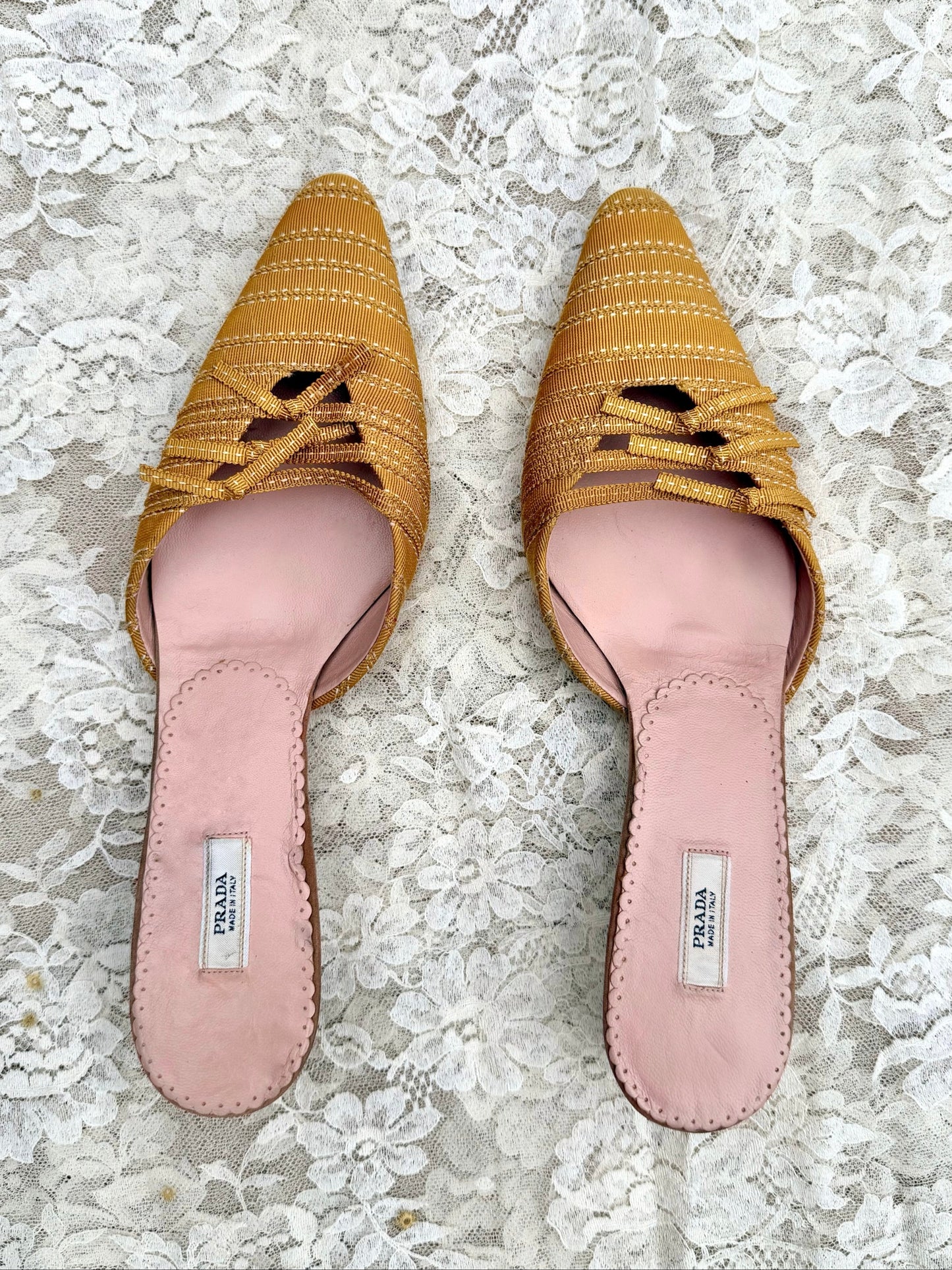 Pair of vintage prada yellow woven shoes with pink soles on a lace background