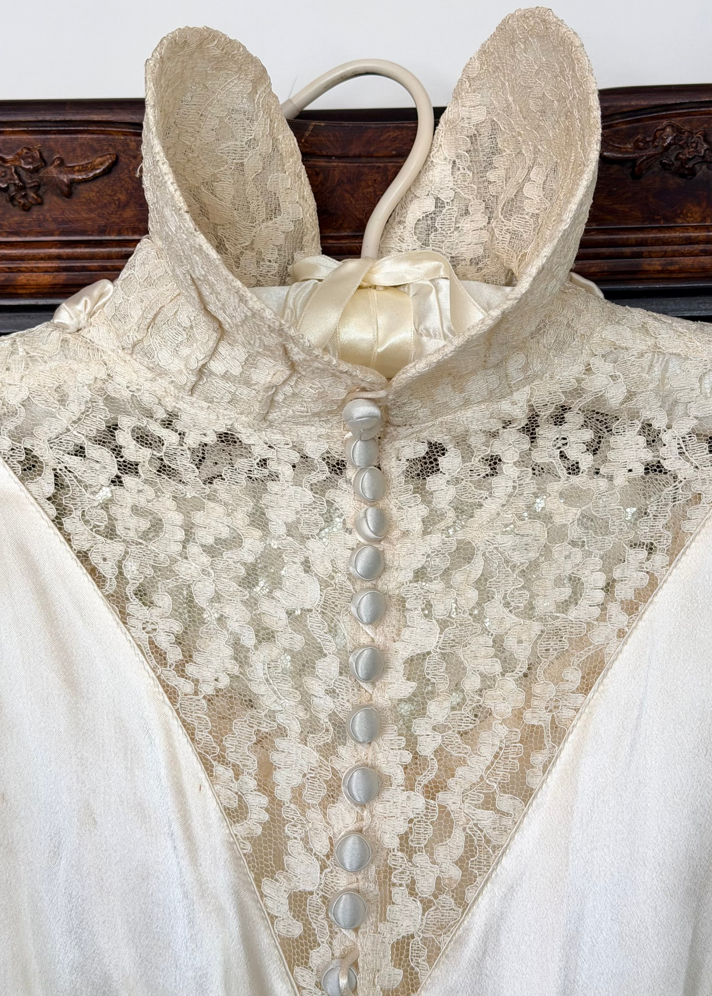 Close-up of a vintage lace garment with buttons against a wooden background
