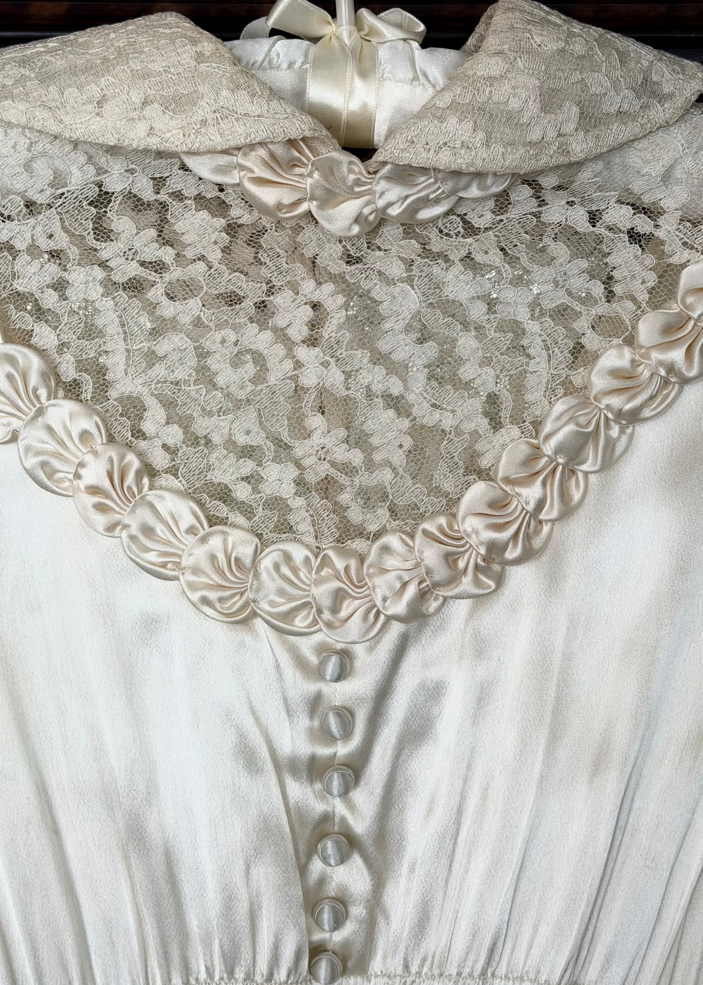 Close-up of a lace-trimmed garment with buttons, likely from an antique dress.