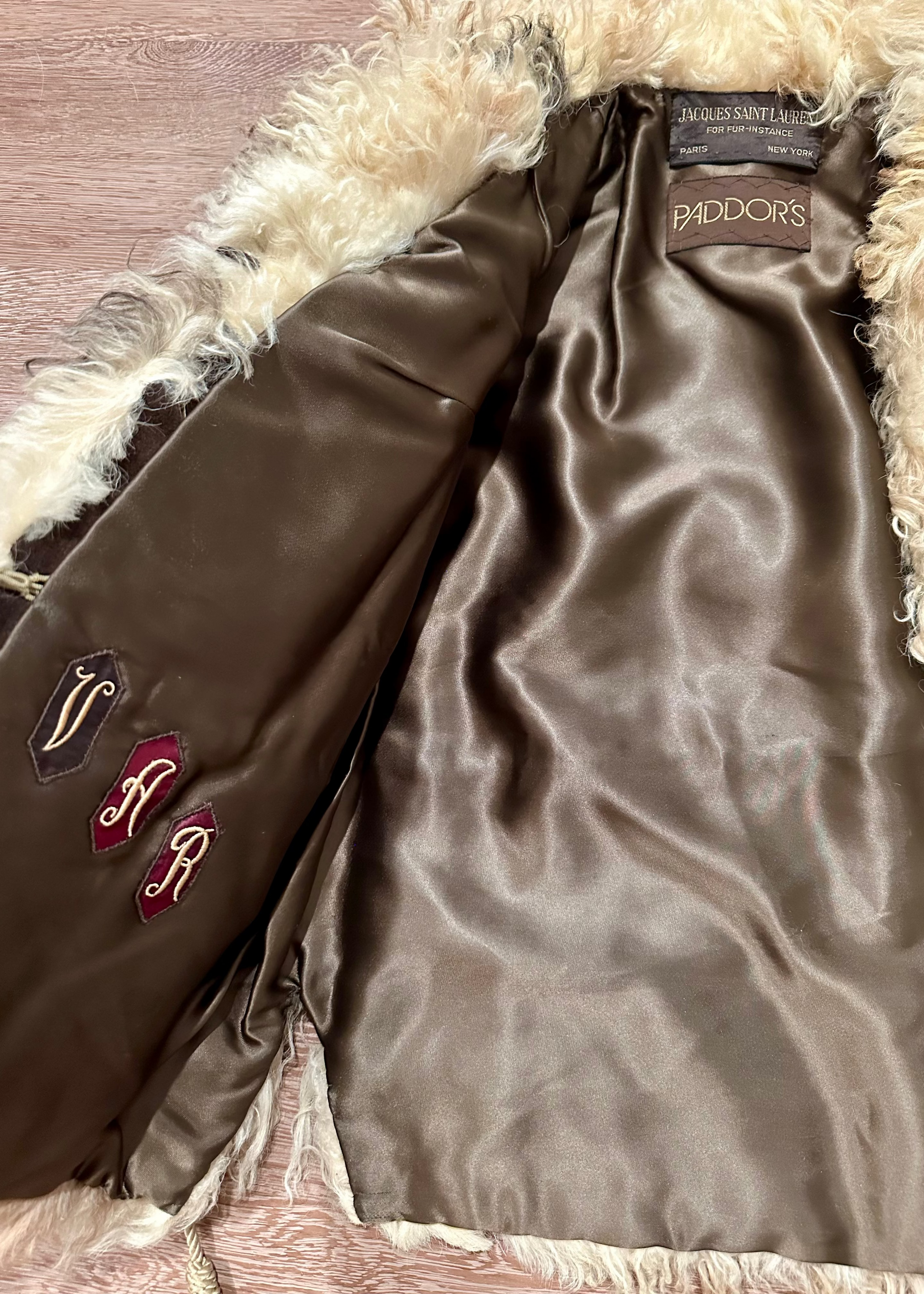 Brown satin garment with fur trim on a textured surface