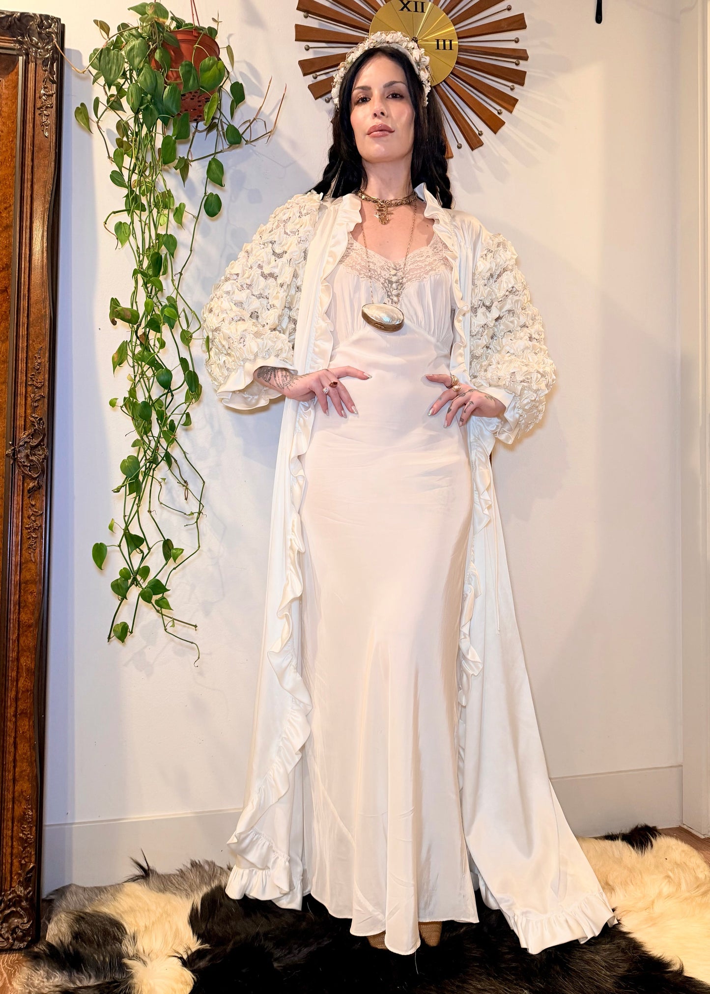 Woman in a white 1930s bias cut dress standing in a room with decorative elements.