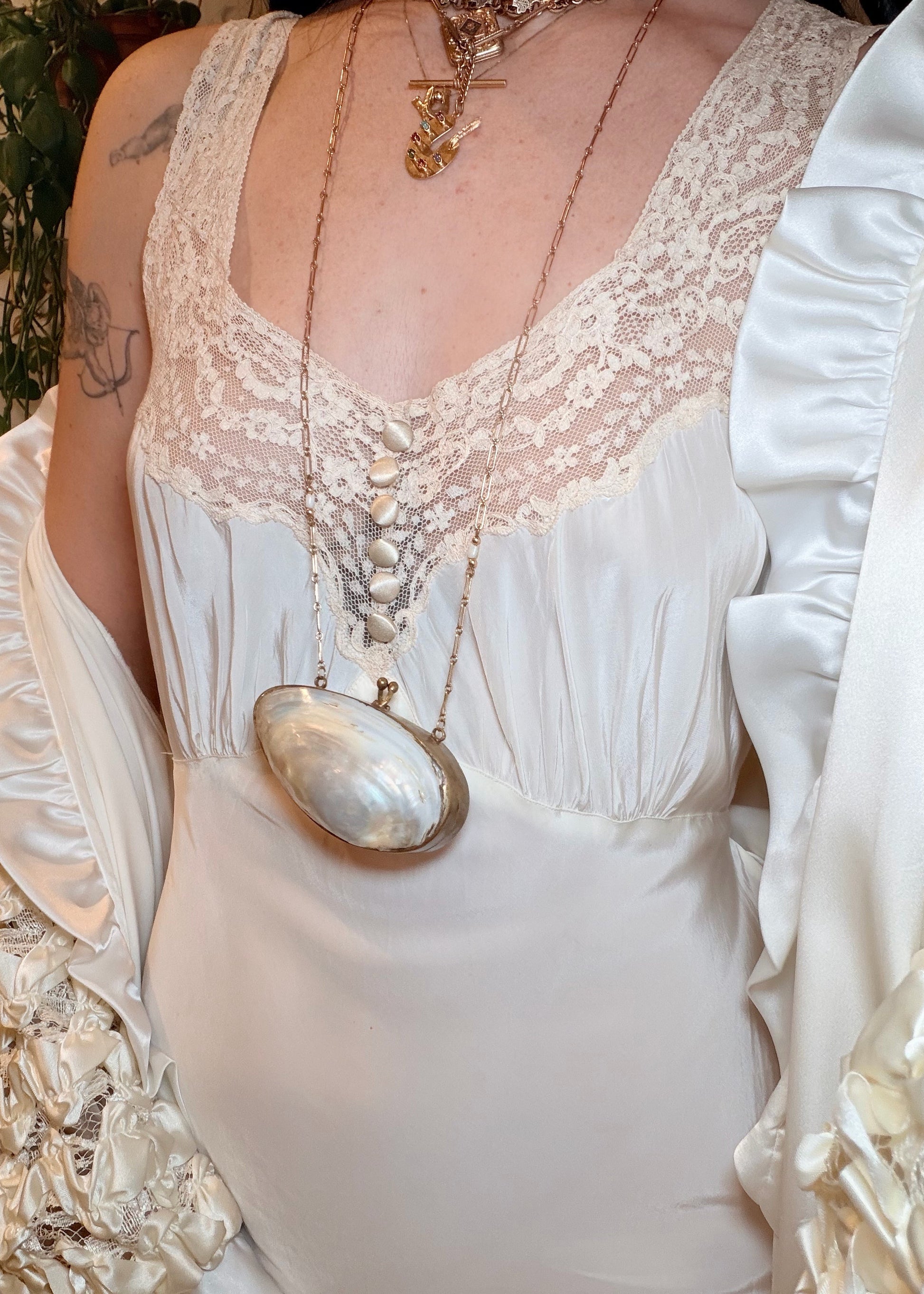 Woman in a white 1930s bias cut dress standing in a room with decorative elements.