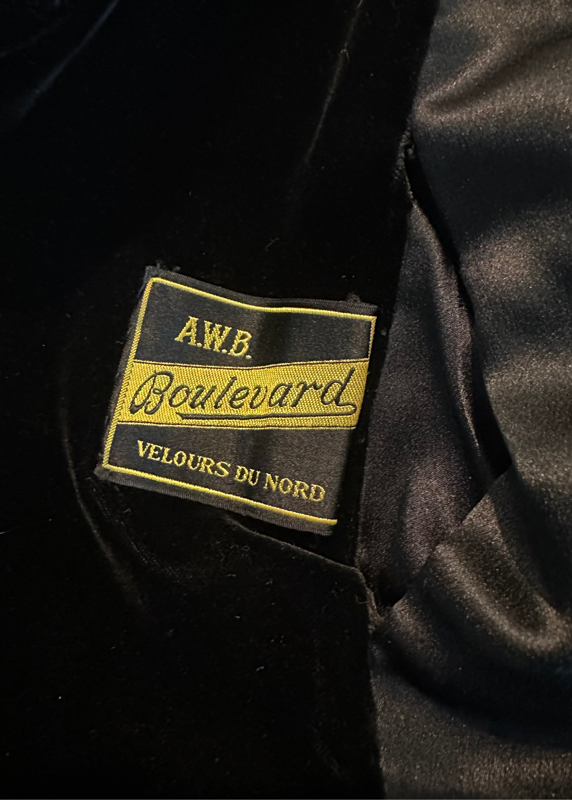 Close-up of a black velvet garment with a gold label reading 'A.W.B. Boulevard Velours Du Nord'.