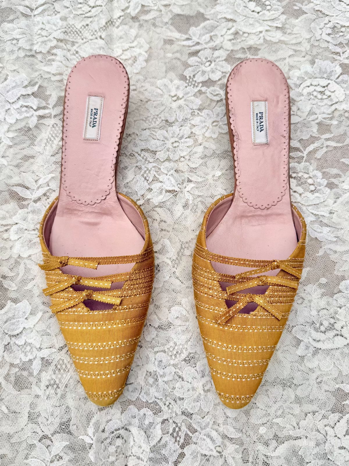 Pair of vintage prada yellow woven shoes with pink soles on a lace background