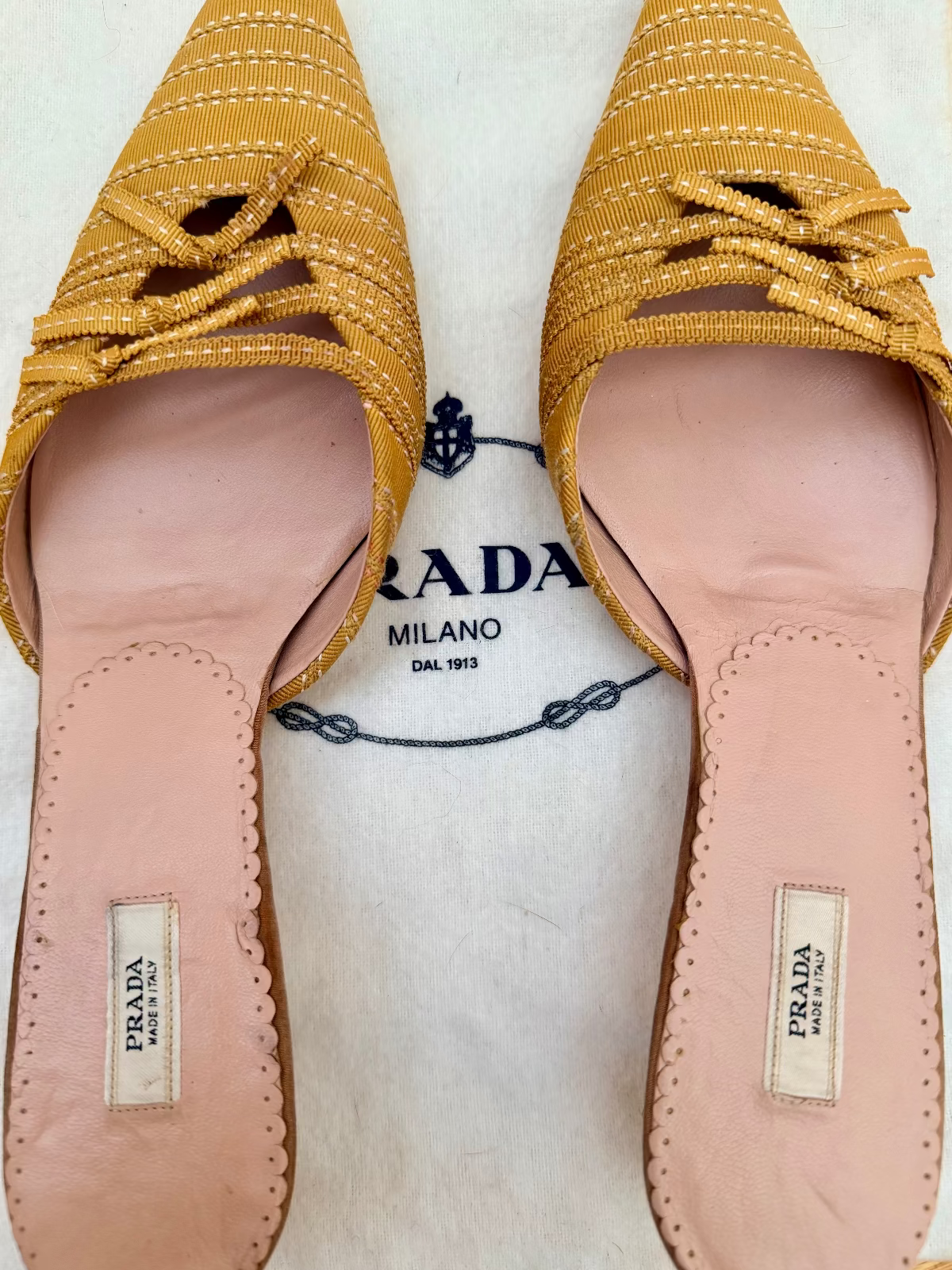 Pair of vintage prada yellow woven shoes with pink soles on a lace background