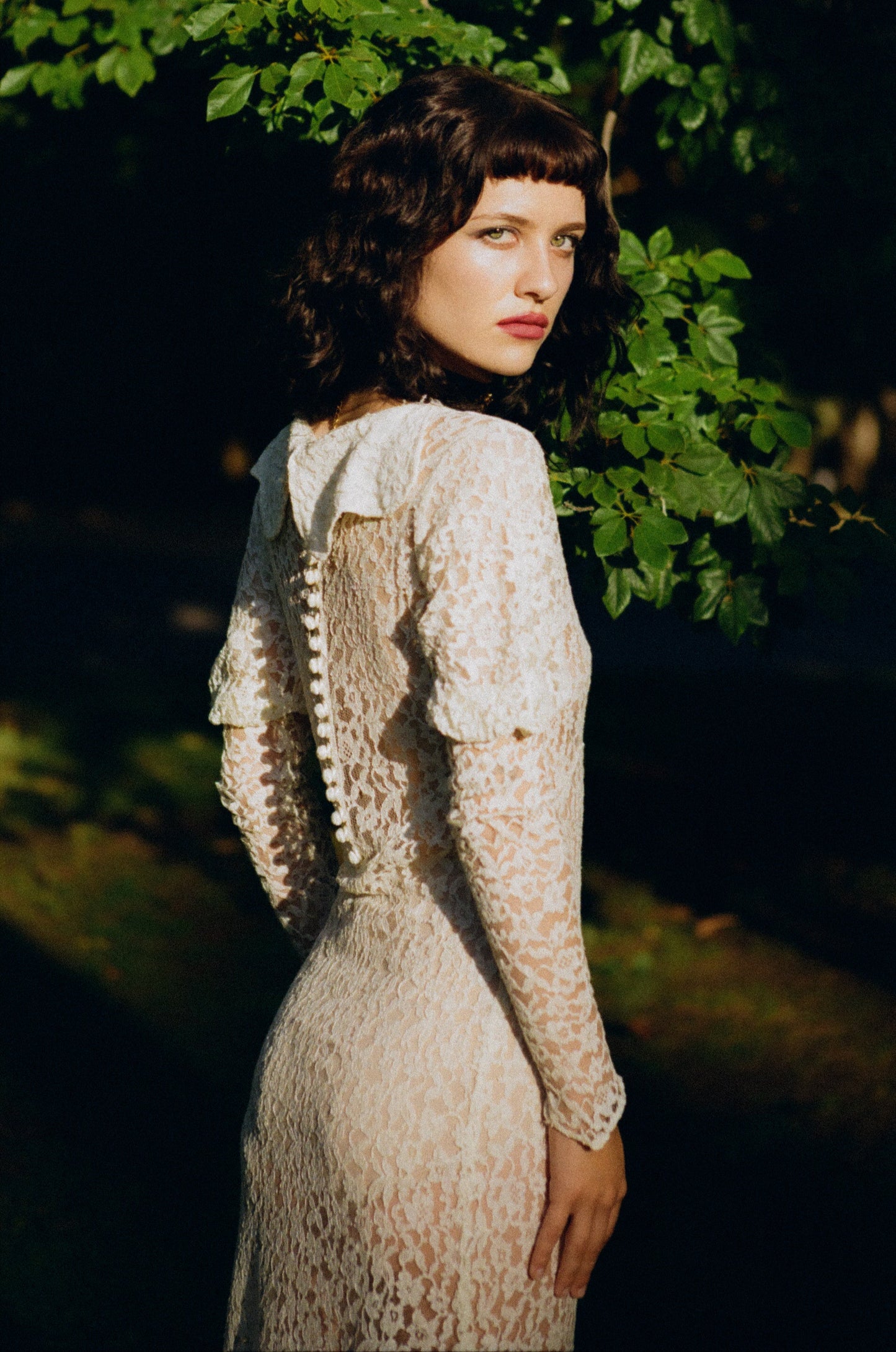 Woman in a lace dress standing in a forest setting