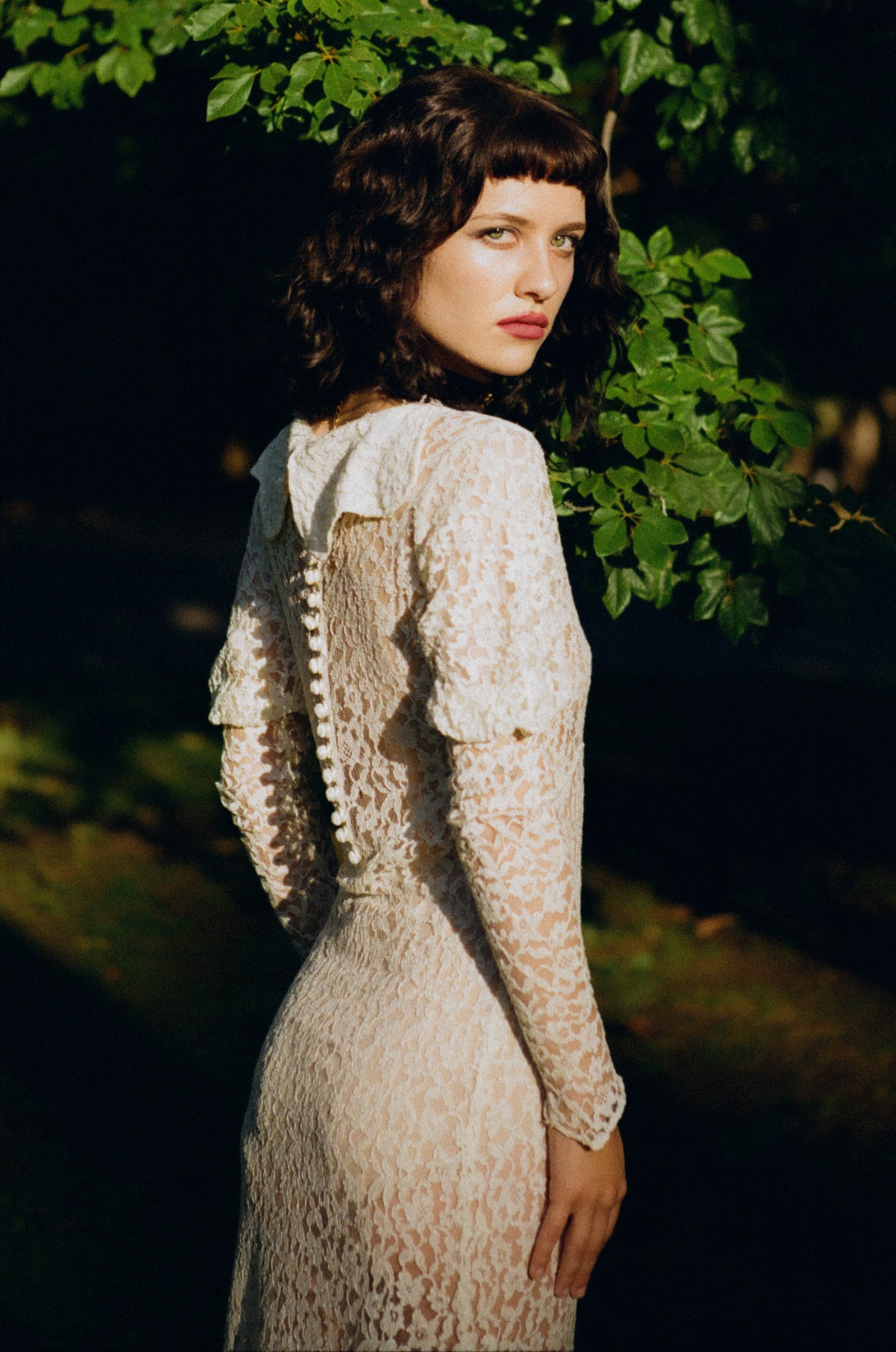 Woman in a lace dress standing in a forest setting