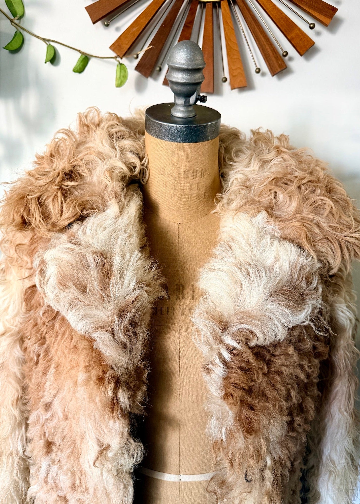 1970's Mongolian curly fur coat in Beige and brown on a mannequin with a neutral background