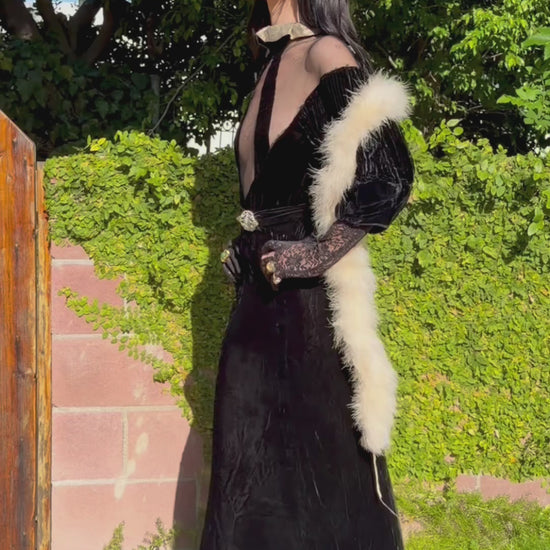 Woman wears antique 1930's black silk velvet Art Deco evening gown in field