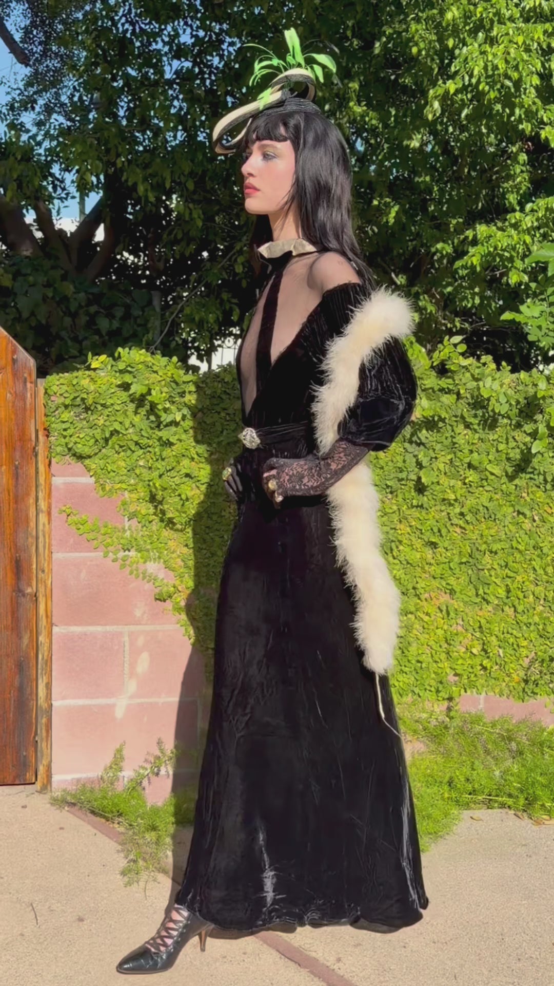 Woman wears antique 1930's black silk velvet Art Deco evening gown in field