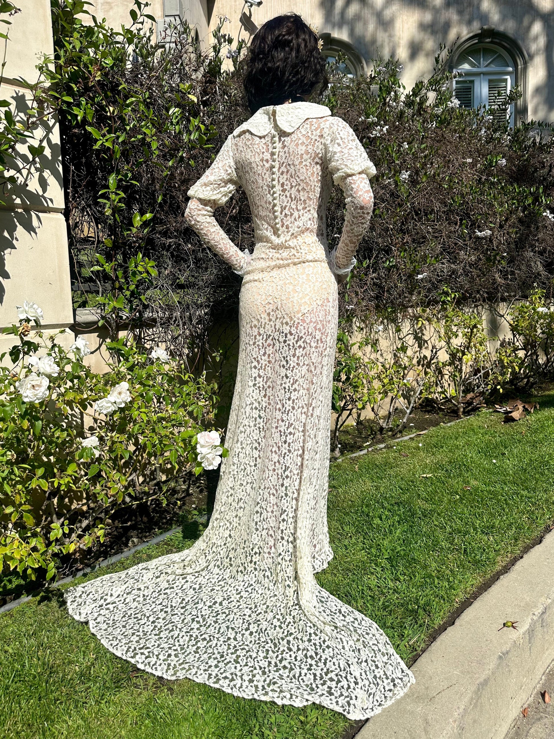 Person wearing a white lace dress standing in a garden.